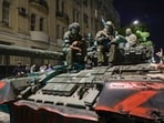 Membes of the Wagner Group military company sit atop of a tank on a street in Rostov-on-Don. 
