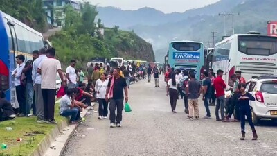 Commuters wait for the clearing of blocked Chandigarh-Manali highway following a landslide triggered by continuous rain in Himachal Pradesh, in Mandi, Monday. (PTI)