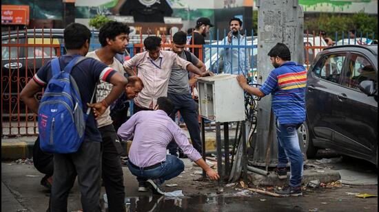 Workers repair an open electric circuit breaker box at New Delhi Railway station parking area on Monday. (Raj K Raj/HT PHOTO)