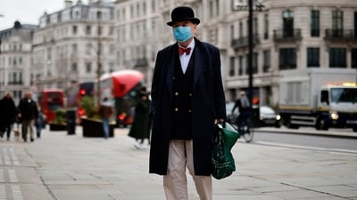 A pedestrian wearing a bow ties and bowler hat along with a face mask or covering due to the COVID-19 pandemic. (AFP) A pedestrian wearing a bow ties and bowler hat along with a face mask or covering due to the COVID-19 pandemic. (AFP)