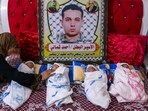 Newborn Palestinian quadruplets, conceived with smuggled sperm from their father imprisoned in Israel and depicted in the placard, are laid on a bed by their grandmother at their home in Gaza city, on June 13.