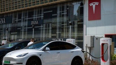 A driver gets into his car at an electric vehicle charging station outside of a Tesla dealership in Beijing, Saturday, June 24. (AP)