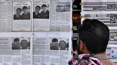 A man looks at morning newspapers as some papers published an ad of condolence messages for two victims of Titan submersible incident, Shahzada Dawood and his son Suleman Dawood (AP Photo/Anjum Naveed) (AP)