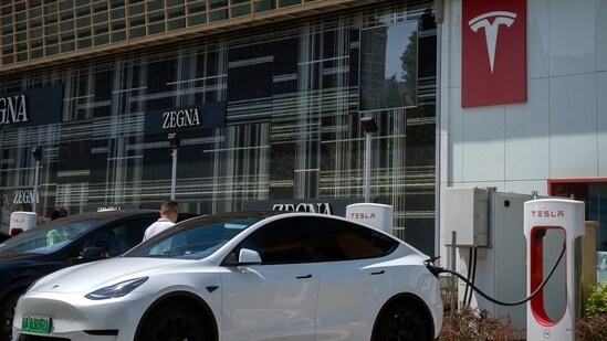 A driver gets into his car at an electric vehicle charging station outside of a Tesla dealership in Beijing. (AP)