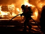 Firefighters extinguish burning vehicles during clashes between protesters and police, after the death of Nael, a 17-year-old teenager killed by French police officer at a traffic stop, in Nanterre, Paris suburb, 