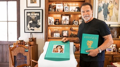 Arnold Schwarzenegger holds up a copy of the new limited edition biography, Arnold. (TASCHEN VERLAG/DW)