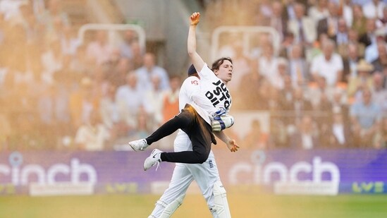 England's Johnny Bairstow carries a Just Stop Oil protester off the pitch during day one of the second Ashes Test. (AP)