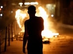A person stands near a burning container as people protest following the death of Nahel, a 17-year-old teenager killed by a French police officer in Nanterre during a traffic stop.