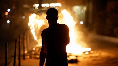A person stands near a burning container as people protest following the death of Nahel, a 17-year-old teenager killed by a French police officer in Nanterre during a traffic stop. (Reuters)