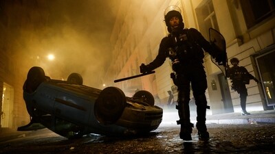 French riot police officers walk next to a vehicle upside down during the fifth day of protests following the death of Nahel, a 17-year-old teenager killed by a French police officer in Nanterre during a traffic stop, in Paris. (REUTERS)