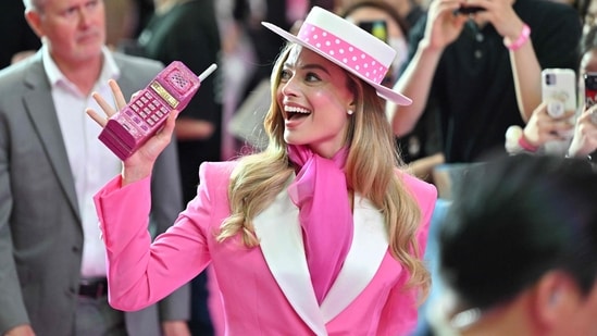 For her first look, Margot Robbie carried several matching accessories, including a rhinestone covered phone, a white hat with a pink band and a small pink Versace purse. On her feet were super tall white heels.(AFP)