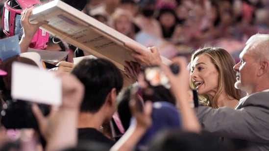 Margot Robbie is greeted by fans during the pink carpet event for the movie Barbie in Seoul. In the irreverent comedy, Barbie (Margot Robbie) and Ken (Ryan Gosling) venture beyond the perfect, pink, plastic dreamland they share with dozens of other Barbies and Kens, and find themselves in the real world, much to the annoyance of a Mattel executive played by Will Ferrell.(AP)