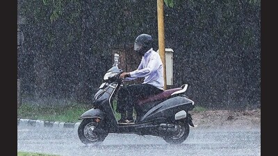 A scooterist caught in the showers on the Sector 33-45 dividing road in Chandigarh. (Keshav Singh/HT)