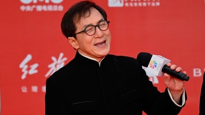 Hong Kong actor Jackie Chan (R) sings as Ethnic Uyghur Chinese actress Gulnezer Bextiyar (L), also known as Gulinazha, looks on as they stand on the red carpet during the opening ceremony of the 13th Beijing International Film Festival (BJIFF) in Beijing, on April 21, 2022. (Photo by Jade GAO / AFP) (AFP)