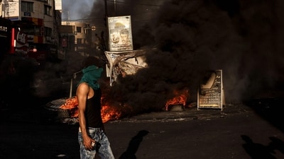 A masked man walks near a fire during clashes with the Israeli army in the occupied West Bank city of Jenin during an ongoing military operation on July 4. Israel unleashed a major raid on July 3 on Jenin refugee camp, a Palestinian militant stronghold in the Israeli-occupied West Bank, killing at least 10 Palestinians in clashes with gunmen, Reuters reported. (Ronaldo Schemidt / AFP) A masked man walks near a fire during clashes with the Israeli army in the occupied West Bank city of Jenin during an ongoing military operation on July 4. Israel unleashed a major raid on July 3 on Jenin refugee camp, a Palestinian militant stronghold in the Israeli-occupied West Bank, killing at least 10 Palestinians in clashes with gunmen, Reuters reported. (Ronaldo Schemidt / AFP)