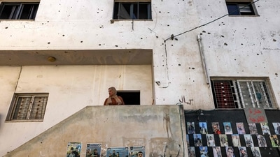 A woman stands outside a building displaying pictures of killed Palestinians, the facade riddled with bullet holes in the occupied West Bank city of Jenin. (Ahmad Gharabli / AFP) A woman stands outside a building displaying pictures of killed Palestinians, the facade riddled with bullet holes in the occupied West Bank city of Jenin. (Ahmad Gharabli / AFP)