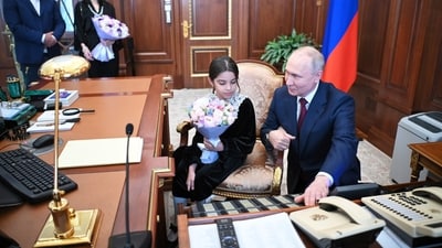 Russian president Vladimir Putin shows 8 year old Raisat Akipova, from Derbent his desk as her parents Akhmet Akipov and Kultum Akipova are seen near at the Kremlin in Moscow. (AP) Russian president Vladimir Putin shows 8 year old Raisat Akipova, from Derbent his desk as her parents Akhmet Akipov and Kultum Akipova are seen near at the Kremlin in Moscow. (AP)
