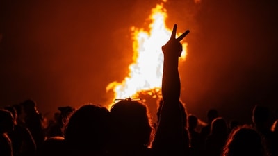 A person throws up a peace sign as the fire burns. (AFP)