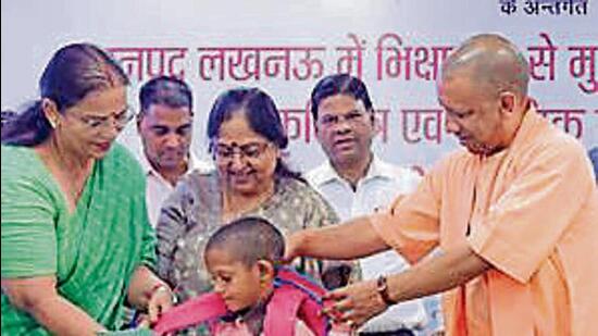 Uttar Pradesh chief minister Yogi Adityanath distributing educational material to a child in Lucknow on Wednesday. (HT PHOTO)