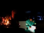 South Africa Gas Leak: A member of the Emergency Medical Services (EMS) writes notes as onlookers gather around a fire near the scene of a suspected gas leak.