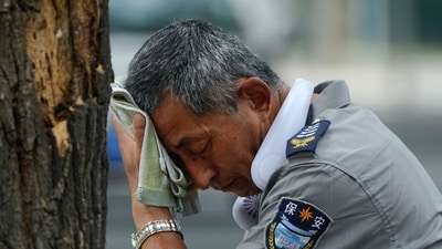 Beijing Heatwave: A security guard wearing an electric fan on his neck wipes his sweat on a hot day in Beijing. (AP) Beijing Heatwave: A security guard wearing an electric fan on his neck wipes his sweat on a hot day in Beijing. (AP)