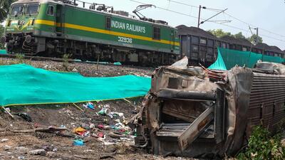 Balasore: A goods train runs past the triple train accident site while at the forefront a mangled coach lays bare, near Bahanga Bazar railway station in Balasore district (PTI Filw Photo)