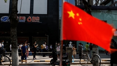 A China's flag flutters near people lining up to get tested at a makeshift nucleic acid testing site. (File image) (REUTERS)
