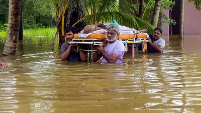 People wade through a flooded area as they carry a sick elderly man to a hospital, in Thiruvalla, Thursday, July 6, 2023. (PTI)