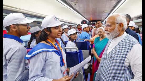 Prime Minister Narendra Modi interacts with students in Vande Bharat Express after its flagging off, in Gorakhpur, Friday. (PTI Photo)