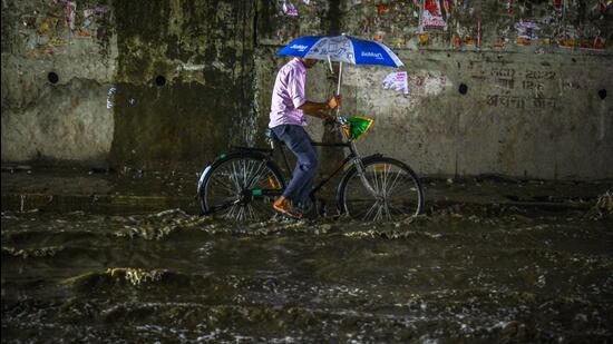 A commuters passes a waterlogged street after heavy rains in New Delhi on Saturday. (Raj K Raj/HT PHOTO)