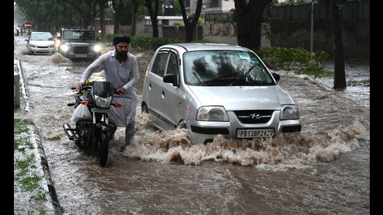 Commuters wading through a waterlogged Sector 36-37 dividing road in Chandigarh on Saturday.A total of 300.1 mm rain has been recorded in July so far. (Sanjeev Sharma/HT)