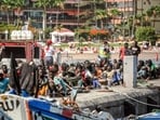 Migrants rest on the pier after disembarking from a 'cayuco' (wooden boat) following a rescue operation on July 4, 