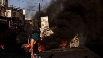 A masked man walks near a fire during clashes with the Israeli army in the occupied West Bank city of Jenin during an ongoing military operation on July 4. Israel unleashed a major raid on July 3 on Jenin refugee camp, a Palestinian militant stronghold in the Israeli-occupied West Bank, killing at least 10 Palestinians in clashes with gunmen, Reuters reported. (Ronaldo Schemidt / AFP) A masked man walks near a fire during clashes with the Israeli army in the occupied West Bank city of Jenin during an ongoing military operation on July 4. Israel unleashed a major raid on July 3 on Jenin refugee camp, a Palestinian militant stronghold in the Israeli-occupied West Bank, killing at least 10 Palestinians in clashes with gunmen, Reuters reported. (Ronaldo Schemidt / AFP)