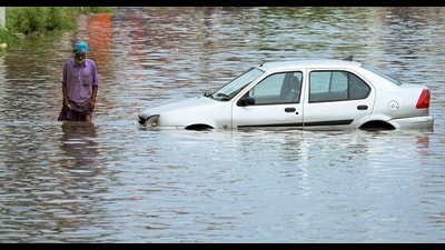 A man wades through the waterlogged road after heavy rainfall in Patiala on Sunday. (ANI)