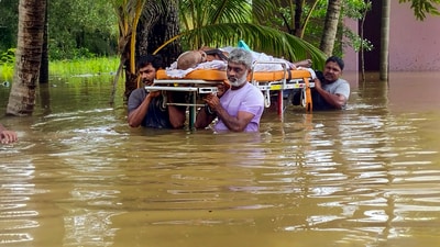 People wade through a flooded area as they carry a sick elderly man to a hospital, in Thiruvalla. (PTI) People wade through a flooded area as they carry a sick elderly man to a hospital, in Thiruvalla. (PTI)