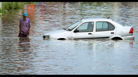 A man wades through the waterlogged road after heavy rainfall in Patiala on Sunday. (ANI)