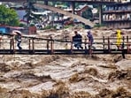 People rush to cross a bridge over the swollen Beas river in Kullu on Monday. (PTI) People rush to cross a bridge over the swollen Beas river in Kullu on Monday. (PTI)