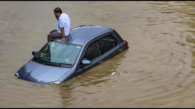 A commuter sits atop a car stuck on a waterlogged road in Haryana. (PTI Photo) A commuter sits atop a car stuck on a waterlogged road in Haryana. (PTI Photo)
