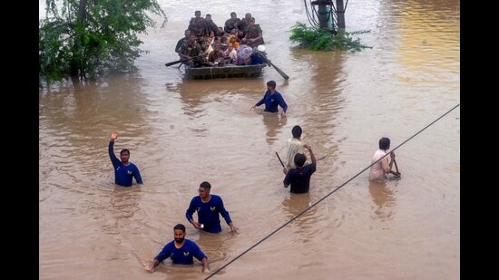 Army personnel and others rescue locals stuck near the flooded Gopal Colony after water level of Badi river rose due to heavy monsoon rains in Patiala on Monday. (PTI)