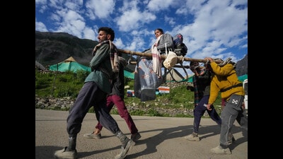 Porters carry an Amarnath pilgrim on a palanquin to the shrine temple from the base camp in Baltal on Tuesday. (PTI)