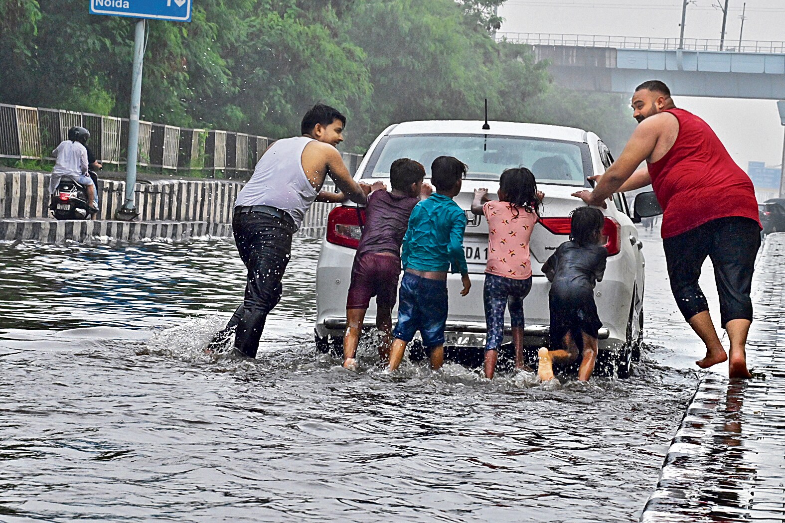 Dum lagake: En route Noida, residents brave the lanes and push a vehicle stuck due to waterlogging. (Photo: Sanjay Sharma/ANI) Dum lagake: En route Noida, residents brave the lanes and push a vehicle stuck due to waterlogging. (Photo: Sanjay Sharma/ANI)
