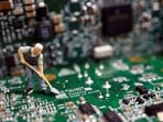 A worker miniature is placed among printed circuit boards with semiconductor chips.