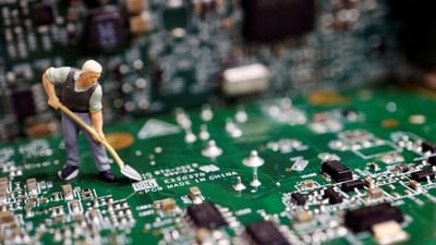 A worker miniature is placed among printed circuit boards with semiconductor chips. (REUTERS)