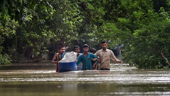 People from low-lying areas around the Yamuna river wade through floodwaters of the swollen river while relocating to a safer place, in New Delhi, Wednesday, July 12, 2023. (PTI)
