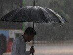 A man shelters under an umbrella during a rainfall. (AFP)