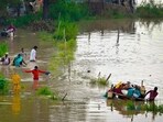 People from low-lying areas around the Yamuna river carry their belongings while relocating to a safer place near Mayur Vihar Phase-1, in New Delhi on Wednesday. People from low-lying areas around the Yamuna river carry their belongings while relocating to a safer place near Mayur Vihar Phase-1, in New Delhi on Wednesday.