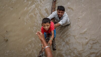 A man helps his son to climb onto a flyover under construction, after being displaced by the rising water level of river Yamuna after heavy monsoon rains in New Delhi. (Reuters)