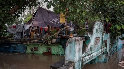A woman prepares food on the roof of her flooded house after a rise in the water level of river Yamuna in New Delhi, India, July 12, 2023. (Reuters)