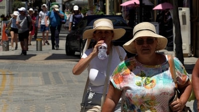 Tourists wear hats and drink water to stay cool as they walk at Ledras street in downtown Nicosia, Cyprus, Thursday. (AP) Tourists wear hats and drink water to stay cool as they walk at Ledras street in downtown Nicosia, Cyprus, Thursday. (AP)