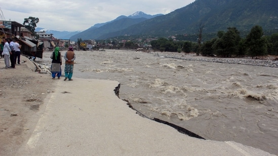 Women stand on a road that got damaged by the flooding of Beas river following heavy rainfall, in Kullu on Thursday.